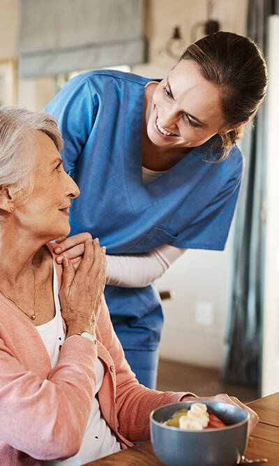 Shot of a young nurse checking up on a senior woman during breakfast at a nursing home